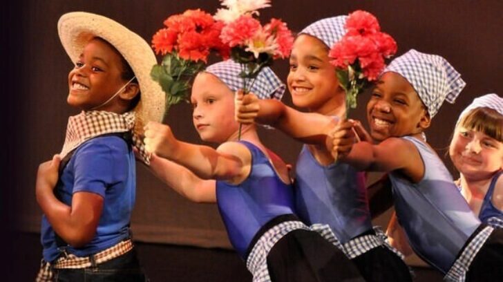 children performing in straw hats and bandanas, holding flowers
