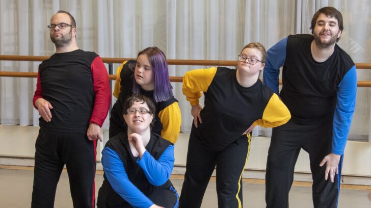 dancers in black shirts with colourful sleeves, having fun and making shapes