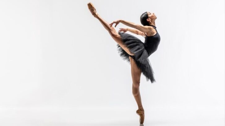 Principle dancer celine in black tutu, with leg and arms back, en pointe
