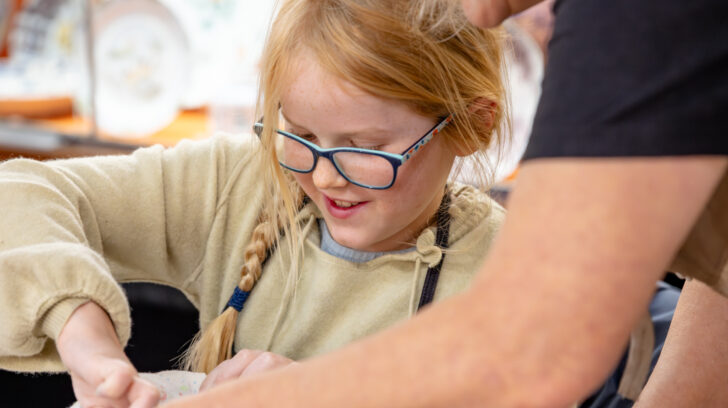 Older woman helps child play with clay