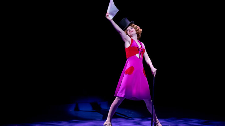 Dancer in pink dress holding up a white paper
